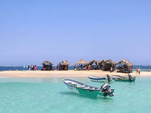 Boote in der Nähe einer kleinen Sandinsel mit Strohhütten