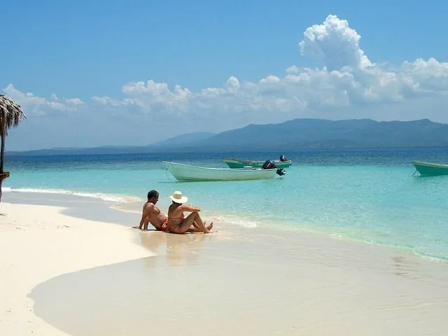 Una pareja relajándose en la playa de arena blanca de Cayo Arena, disfrutando de aguas azules y cristalinas.