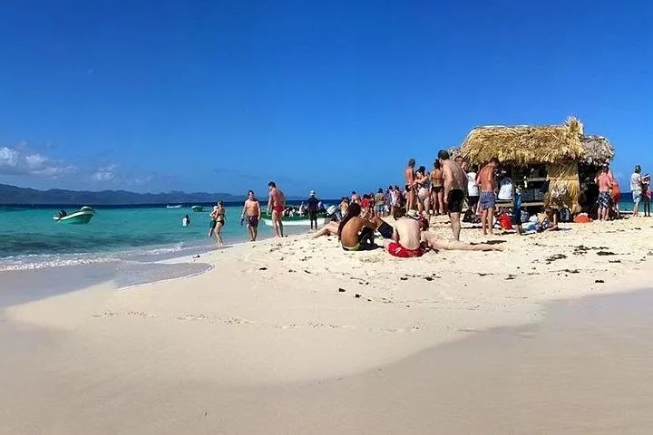 Eine belebte Szene an der Cayo Arena mit vielen Touristen, die sich am Strand entspannen und spazieren gehen.