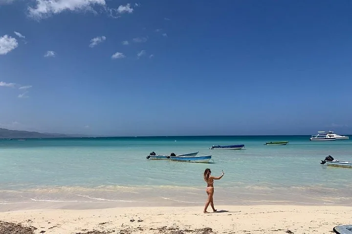 Frau, die auf einem weißen Sandstrand mit kleinen Booten ein Selfie macht