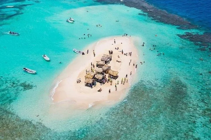 Luftaufnahme von Cayo Arena mit Strohhütten, Booten und badenden Menschen