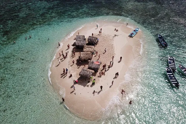 Luftaufnahme einer kleinen Sandinsel mit Hütten und vielen vergnügten Touristen.